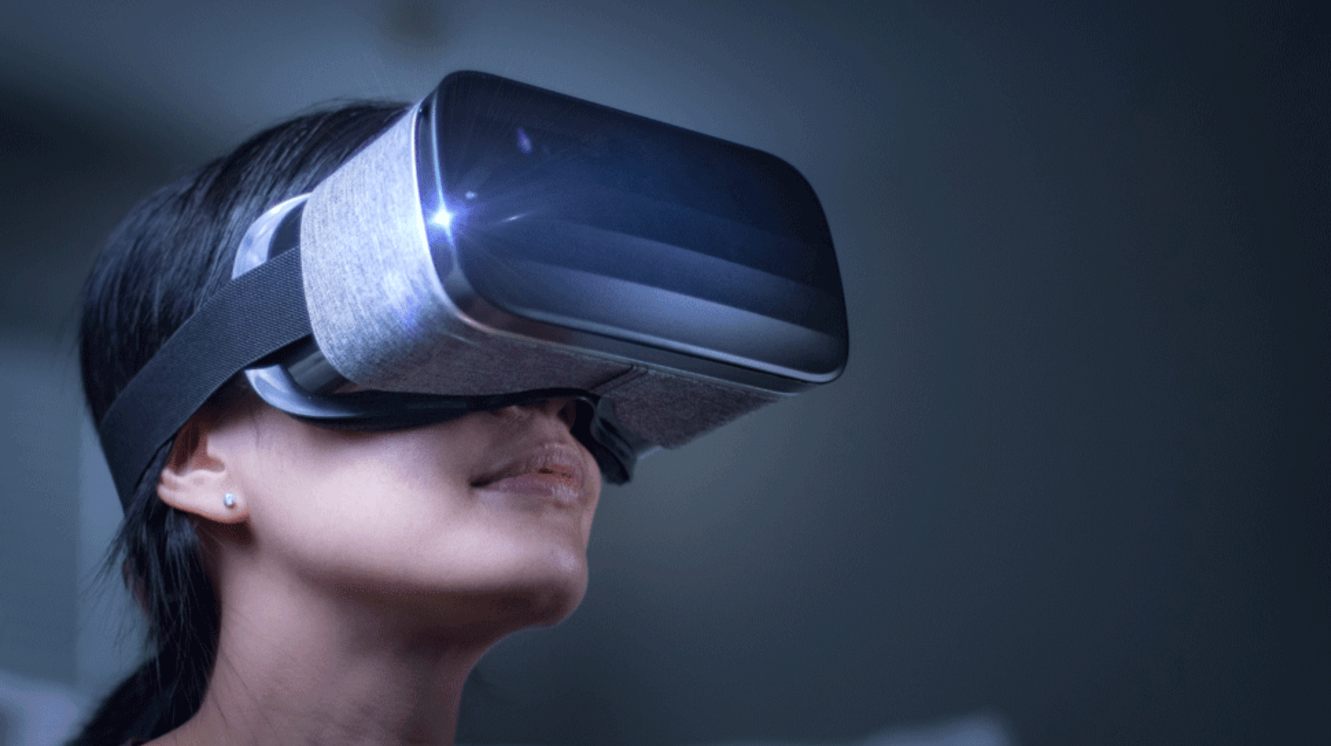Smiling woman wearing a fabric-covered VR headset in a dark room
