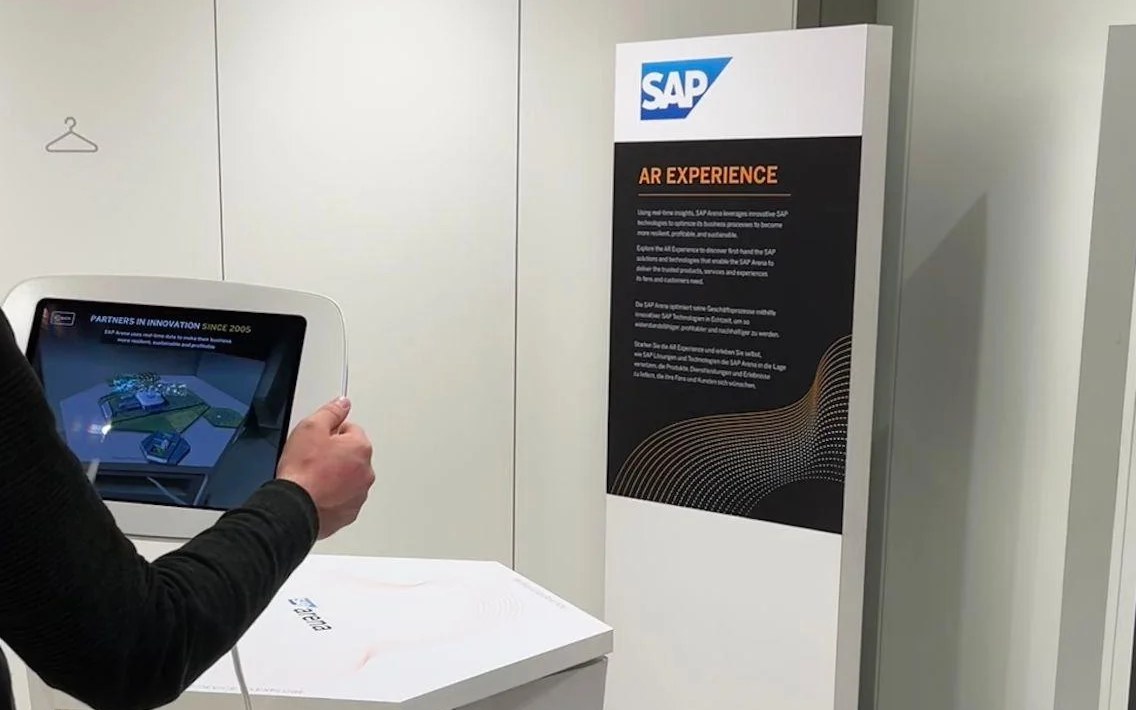 The AR experience running on the branded SAP kiosk’s tethered tablet, next to the bilingual AR Experience banner