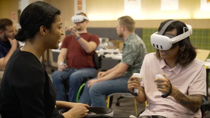 Young man in a Meta Quest 3 headset holding controllers while chatting with a woman, with other users behind